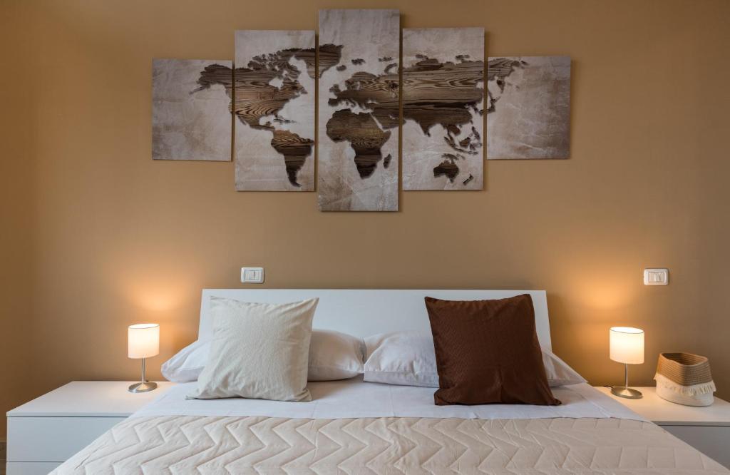 um quarto com uma cama com quatro pinturas na parede em Relax Ciampino - By Good Time Apartments em Ciampino