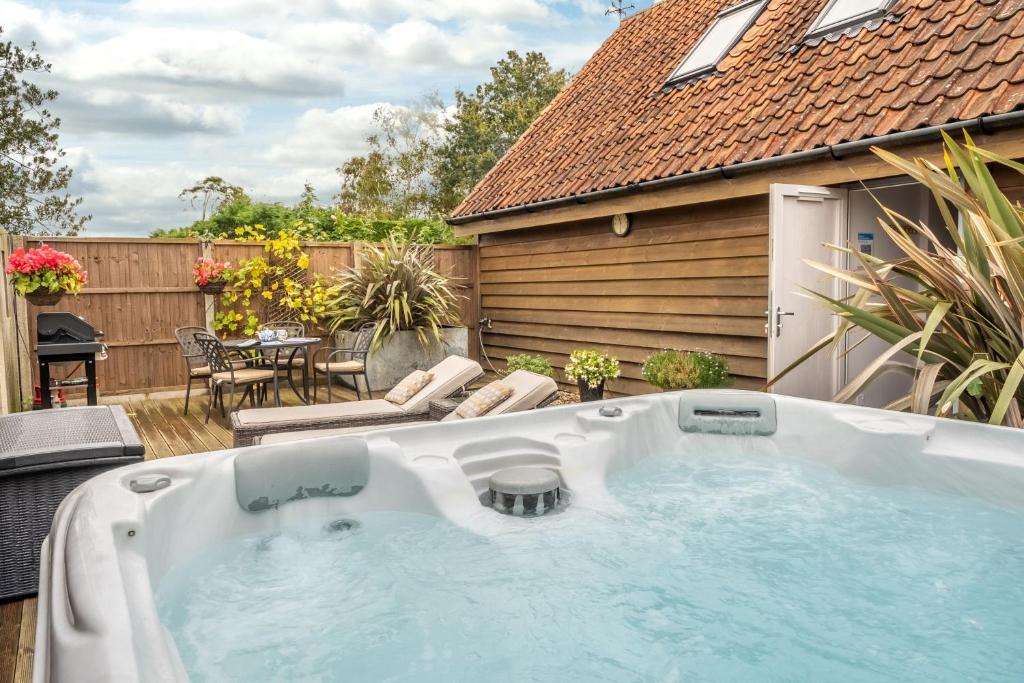 a hot tub in the backyard of a house at Cartshed Lodge in Hoveton