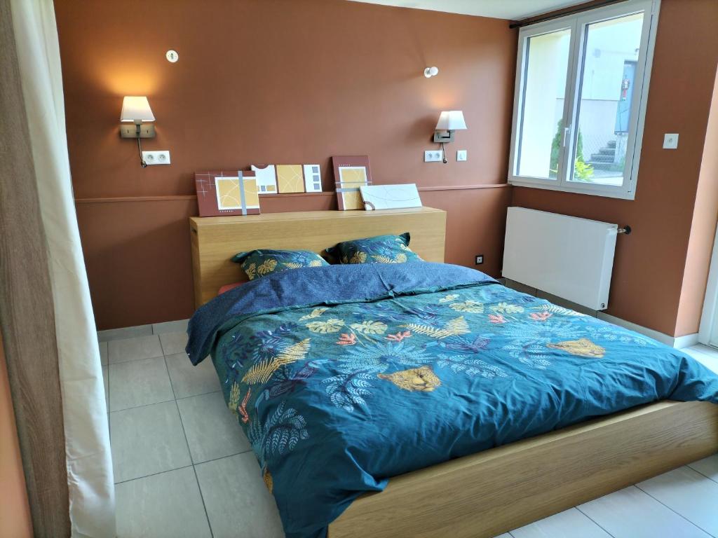 een slaapkamer met een bed met een blauw dekbed en een raam bij L'échappée Comtoise in Baume-les-Dames