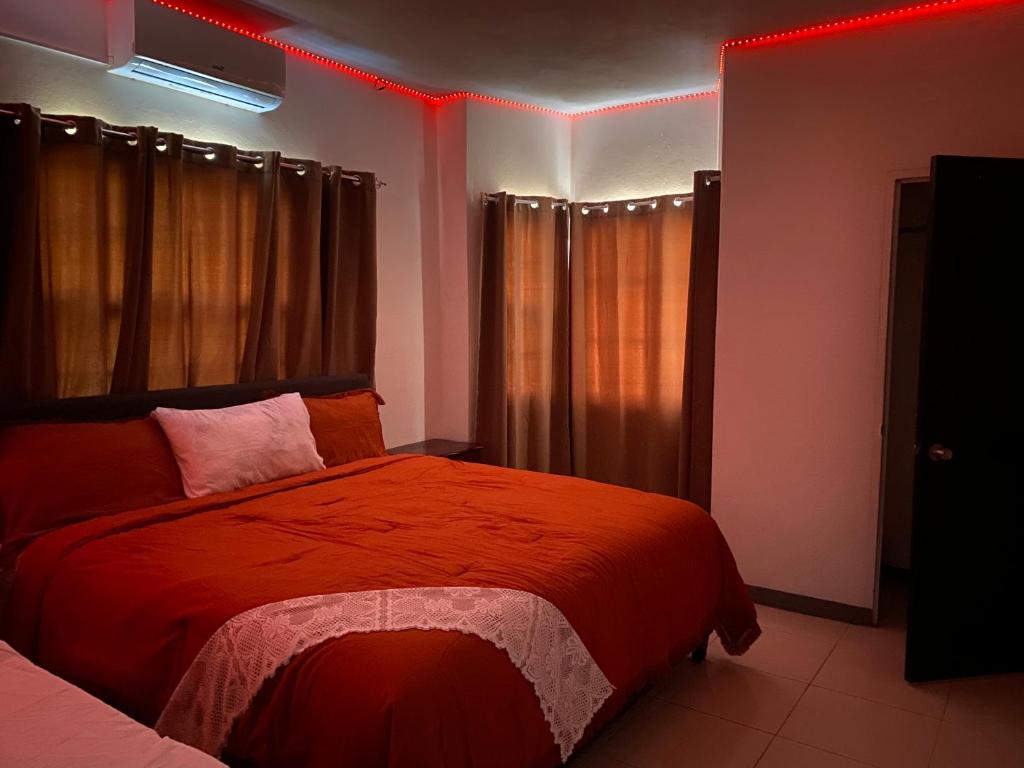 una camera da letto con un letto con luci rosse sopra di Weekendz- Cozy 2BRD Suite a Port Antonio