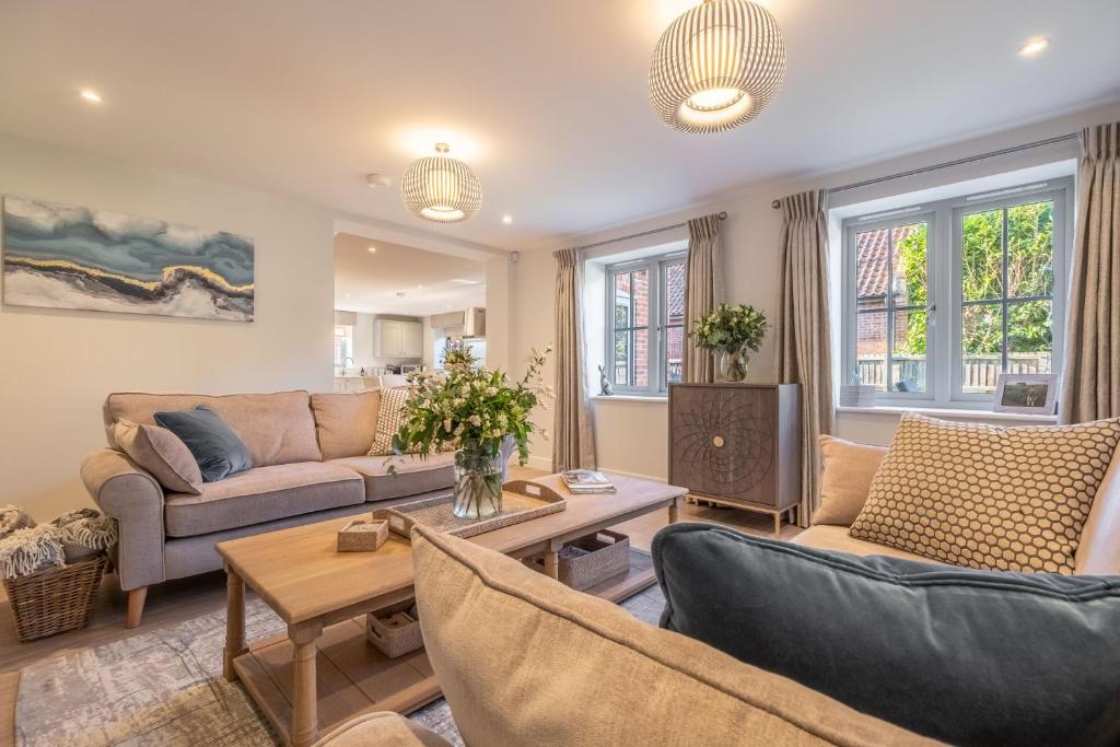 a living room with two couches and a table at Bluebell Cottage in Thornham