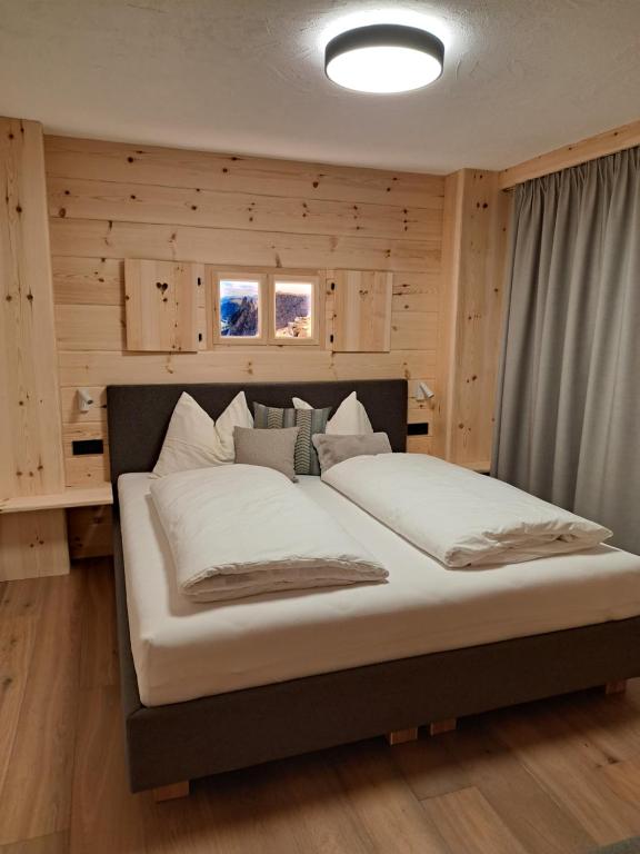 - un grand lit dans une chambre dotée de murs en bois dans l'établissement Pliegermoar in Völs am Schlern, à Vols am Schlern