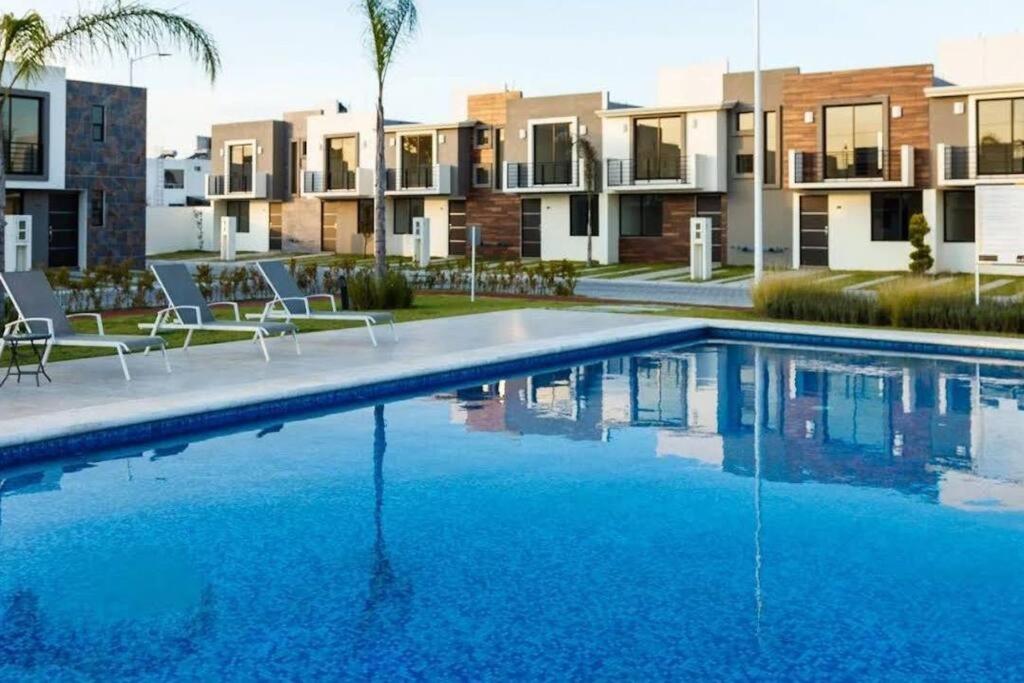 a swimming pool with chairs and buildings in the background at Básico Departamento in Puebla