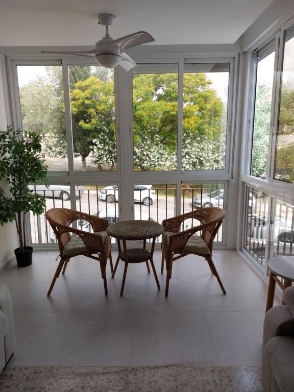 um quarto com uma mesa, cadeiras e janelas em AMPURDAN Bella Vista em Torre del Mar