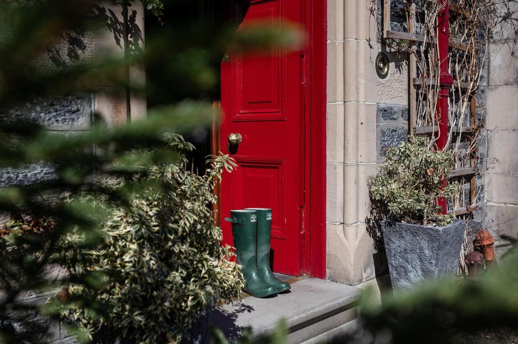 a red door with a green boot in front of it at Strathallan Bed and Breakfast in Grantown on Spey