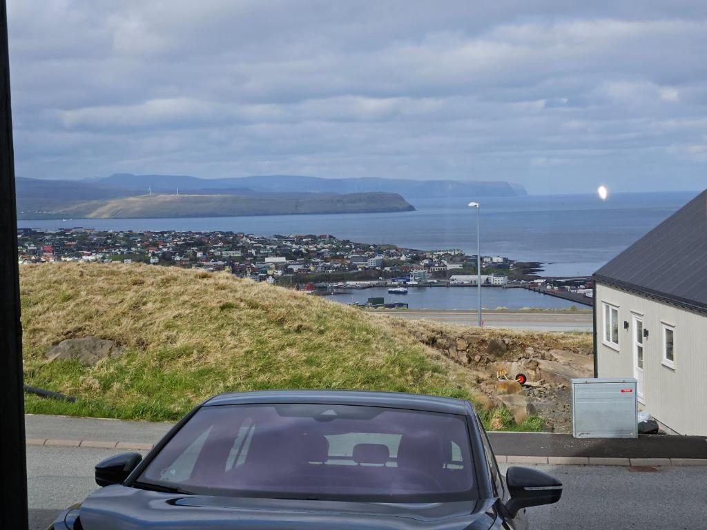 un coche aparcado al lado de una carretera cerca del océano en Brand new apartment with stunning skyline views en Tórshavn