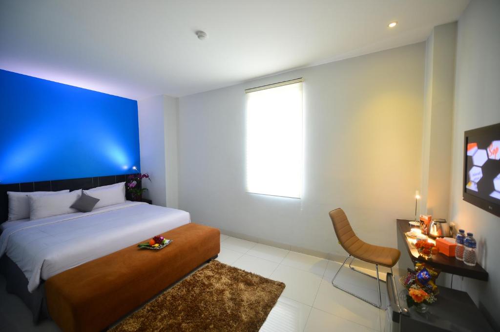 Schlafzimmer mit einem großen Bett mit blauem Kopfteil in der Unterkunft J Hotel - Bandara Soekarno Hatta in Tangerang