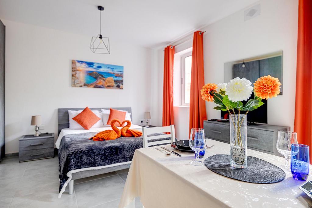 a bedroom with a bed and a table with a vase of flowers at Modern Studio Central Location in Sliema