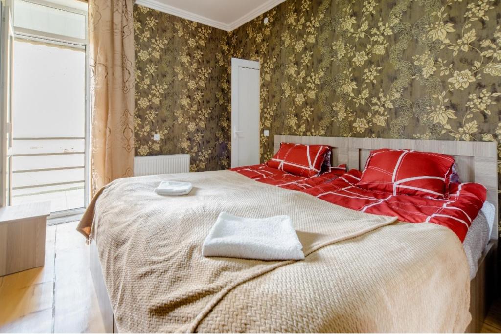 a bedroom with a large bed with red pillows at Hotel Garbani in Stepantsminda