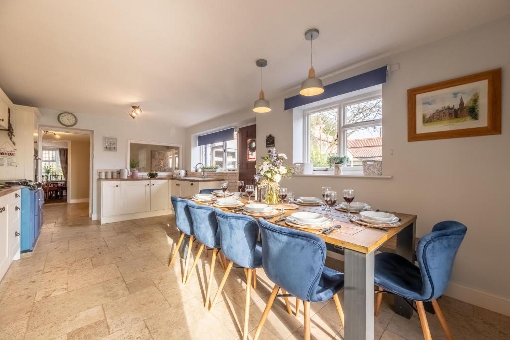 a kitchen and dining room with a table and blue chairs at Homestead in Northrepps