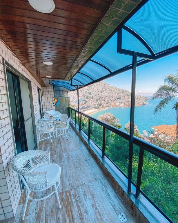 einen Balkon mit Tischen und Stühlen und Blick auf das Wasser in der Unterkunft Apartamento no Porto Real Resort com vista para praia para 6 adultos e 4 adolescentes in Mangaratiba