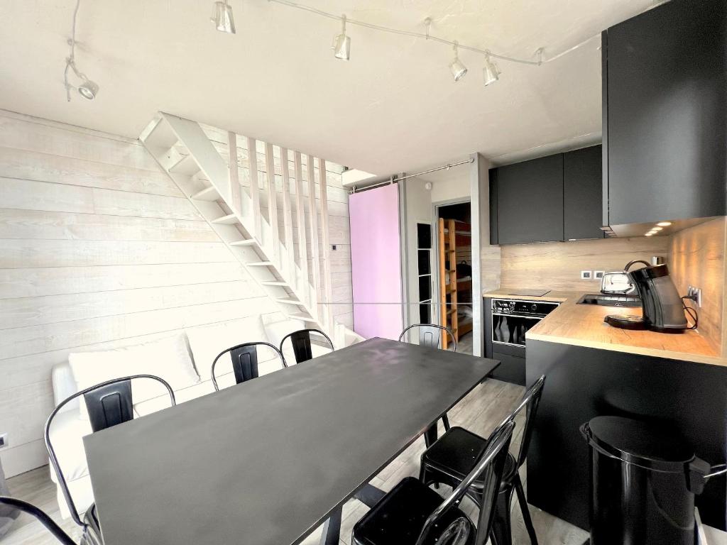 uma cozinha com armários pretos e uma mesa com cadeiras em Duplex 45 m2, 8 couchages, vue imprenable em LʼHuez