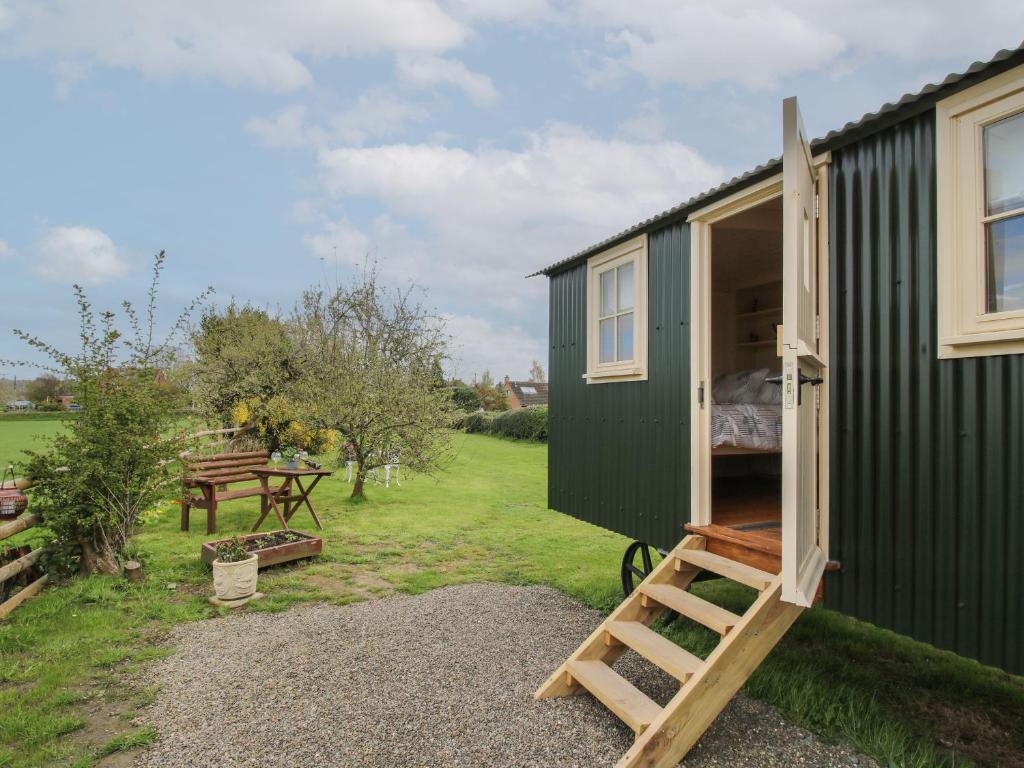 a green tiny house with a ladder in a yard at Le Petite Pound House in Kidderminster