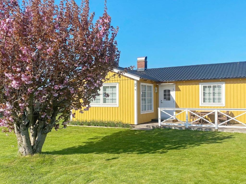Tvååker的住宿－Two-Bedroom Holiday home in Tvååker，前面有一棵树的黄色房子