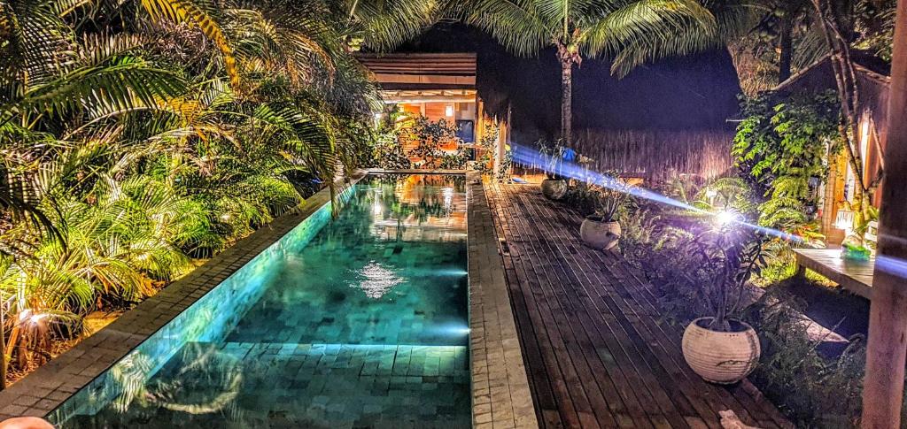a swimming pool in a garden with palm trees at Caiçara Bangalôs Barra Grande Maraú-BA in Barra Grande