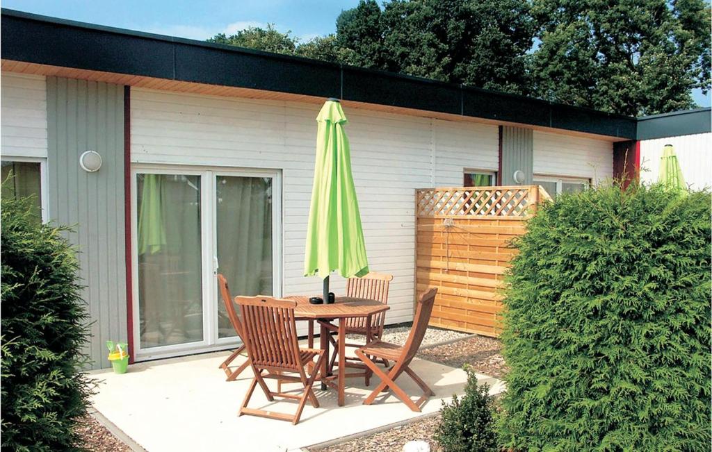 eine Terrasse mit einem Tisch und einem grünen Sonnenschirm in der Unterkunft Ferienhaus Seeigel L in Süssau