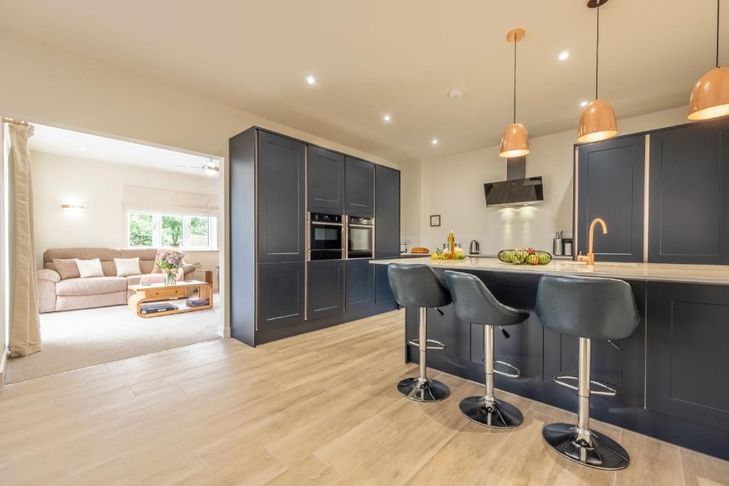 a kitchen with black cabinets and a counter with bar stools at Hedgerows 8 in Burnham Market