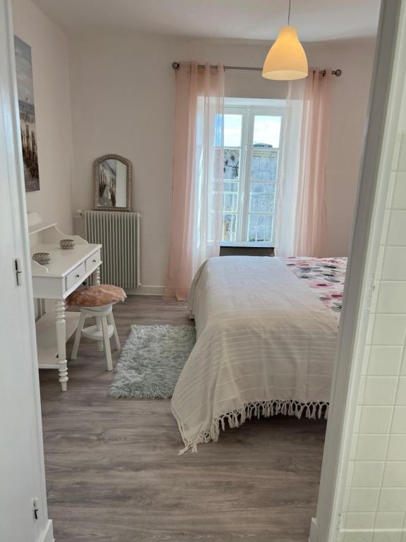 1 dormitorio con cama, escritorio y ventana en Le Loriot, en Champagne-et-Fontaine