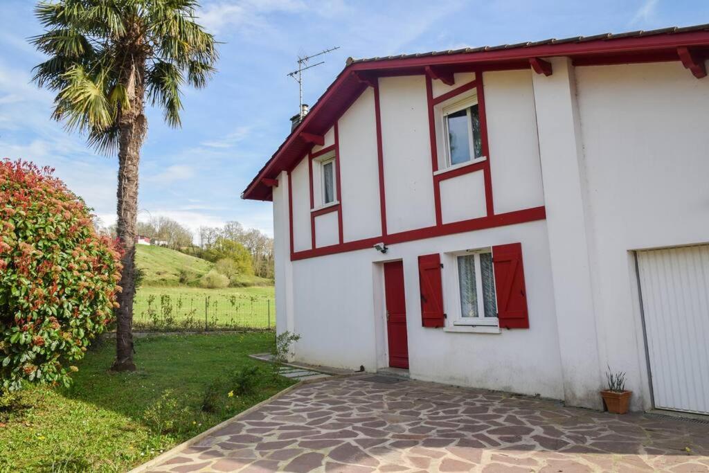 una casa blanca con adornos rojos y una palmera en Maison au cœur du Pays Basque, en Cambo-les-Bains