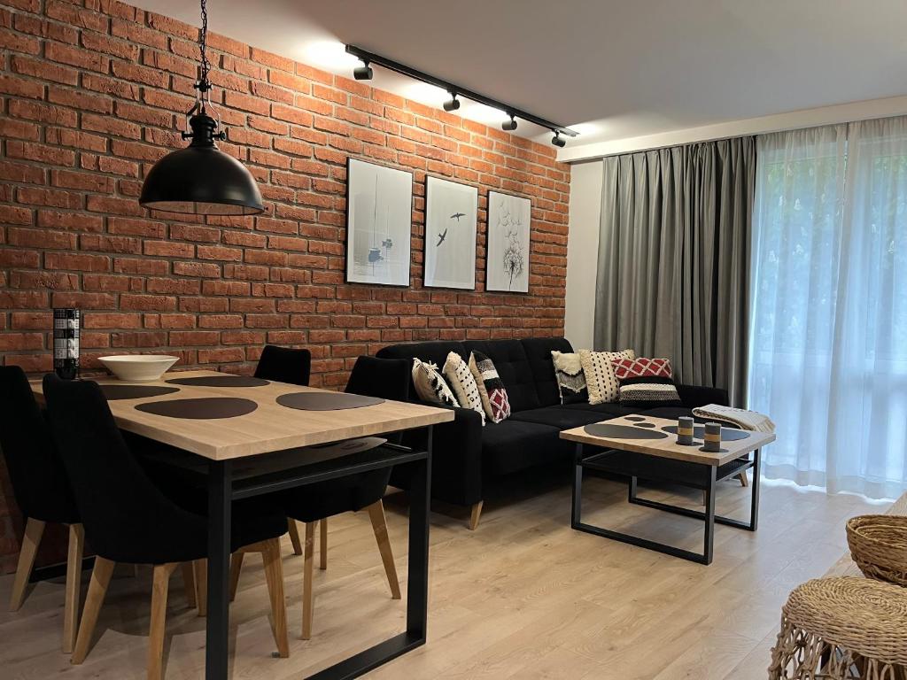 een woonkamer met een tafel en een bakstenen muur bij Apartament Śródmieście in Augustów