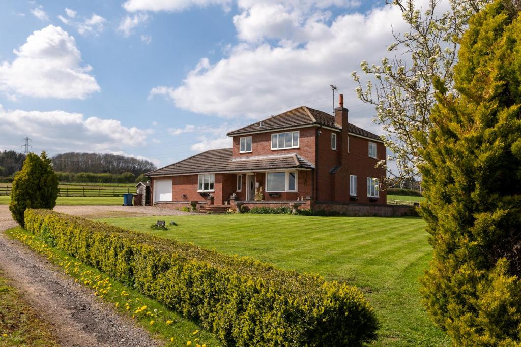 une grande maison en briques avec une cour herbeuse dans l'établissement Tixall Manor Farm, à Stafford