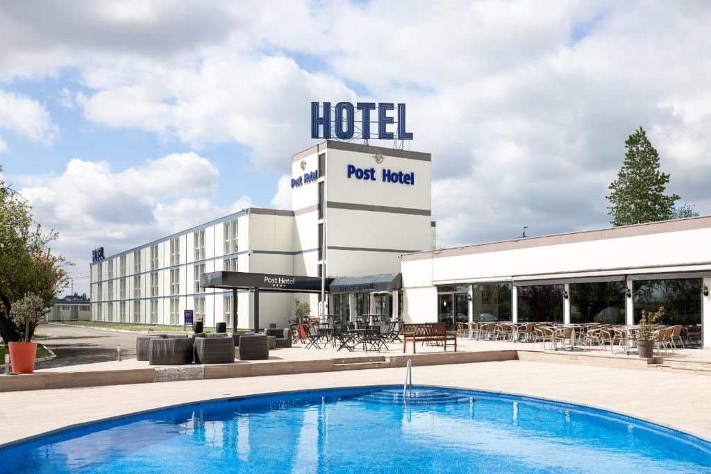 un hotel con piscina frente a un edificio en Globales Post Hotel & Wellness, en Herstal