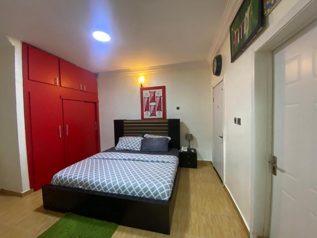 a bedroom with a bed and a red door at Studio C, (Studio Apartment) Hillside Gardens in Lagos