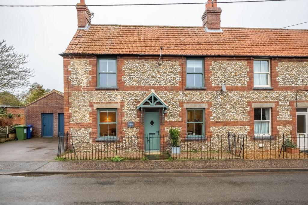 an old brick house with a blue door at Maurice Cottage in Docking