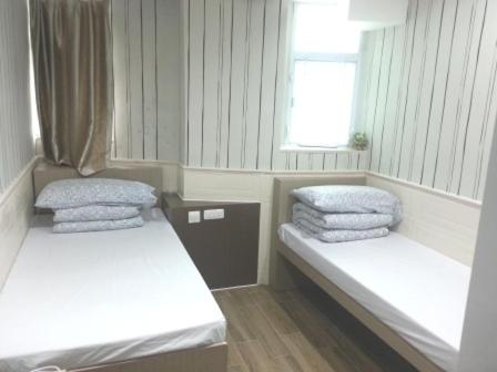 een kleine kamer met 2 bedden en een raam bij K & B Hostel in Hong Kong
