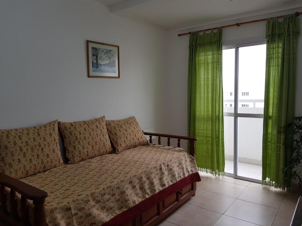 1 dormitorio con sofá y ventana con cortinas verdes en Hermoso Departamento en Salta en Salta