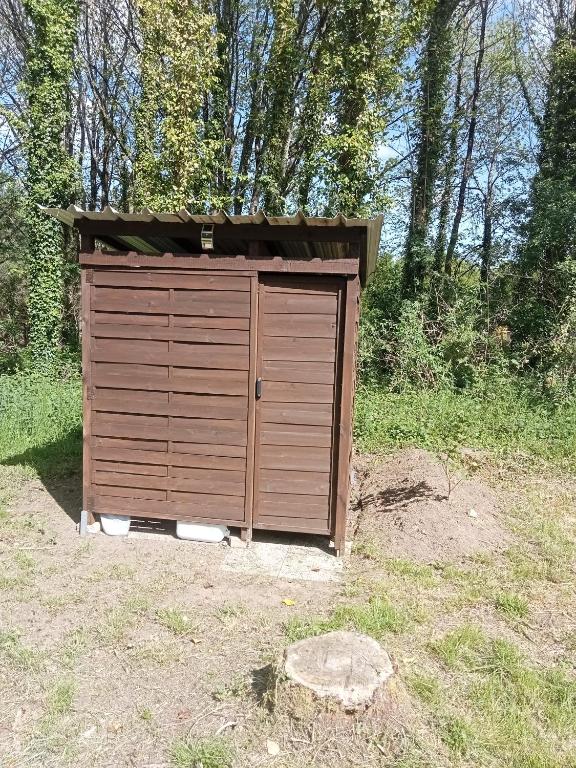 une maison en bois dans un champ avec des arbres dans l'établissement tente nature, à Plouray 2 autres photos