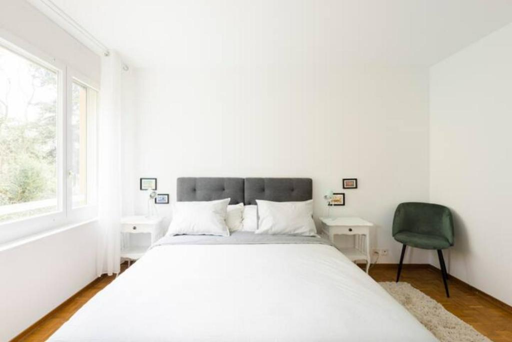 um quarto branco com uma cama grande e uma cadeira verde em Apartment of 52 sqm with free parking em Lausanne