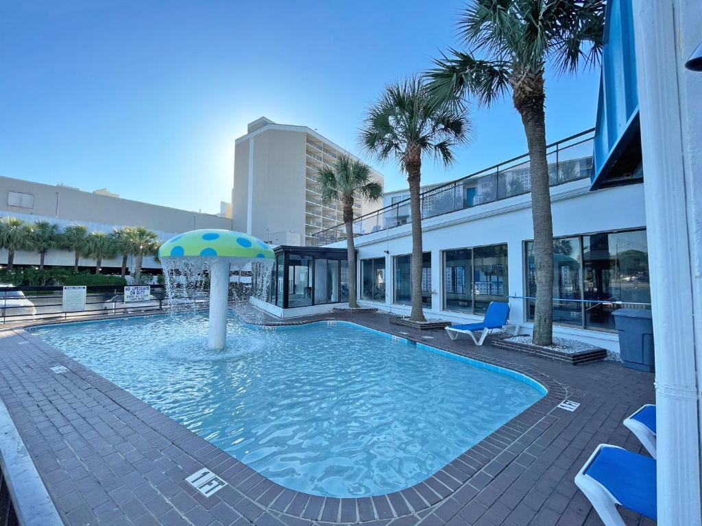 einem Pool mit Sonnenschirm in der Mitte eines Gebäudes in der Unterkunft Polynesian Oceanfront Hotel in Myrtle Beach