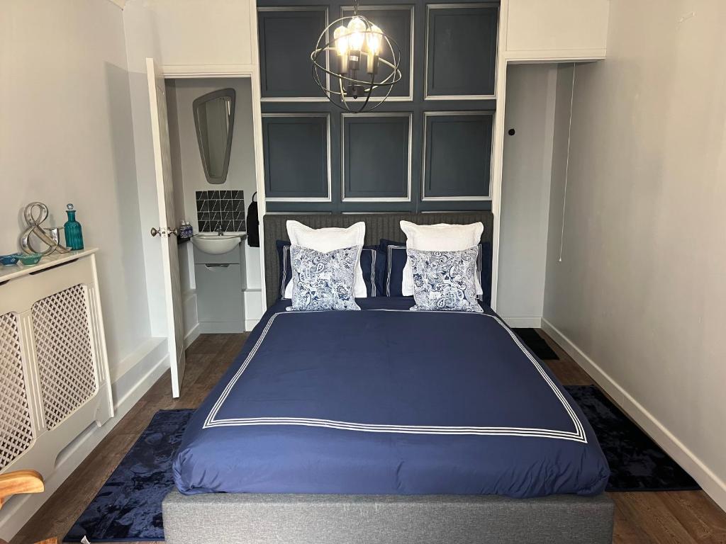 a bedroom with a blue bed and a chandelier at Glastonbury Hideaway in Glastonbury