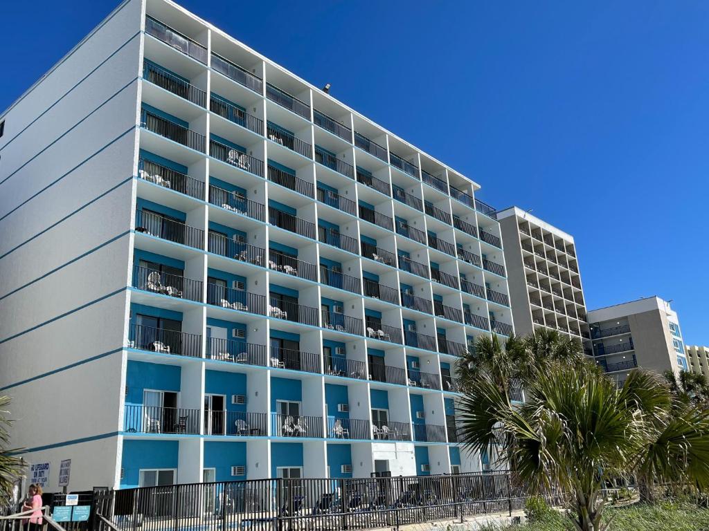 ein großes weißes Gebäude mit Palmen davor in der Unterkunft Polynesian Oceanfront Hotel in Myrtle Beach