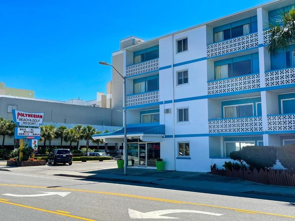 默特爾海灘的住宿－Polynesian Oceanfront Hotel，前面有一辆汽车停放的白色建筑