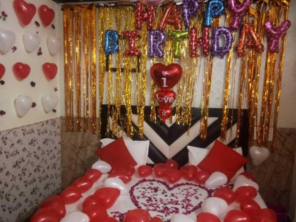 a bed with red and white balloons and a happy birthday sign at OYO Green Villa in Meerut