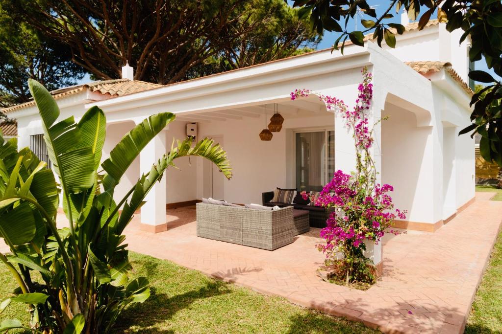 un patio de una casa con flores rosas en Villa Alemania Chalet Independiente con Piscina en Urbanización Roche Conil Cádiz Andalucía España en Roche