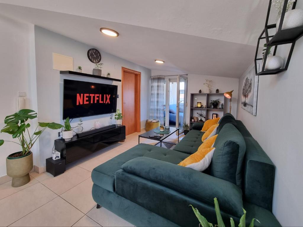 a living room with a green couch and a television at Sunset View Biograd in Biograd na Moru