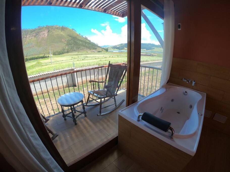 ein Badezimmer mit einer Badewanne und einem Stuhl auf dem Balkon in der Unterkunft Alojamiento Exclusivo en el Valle Sagrado in Cusco