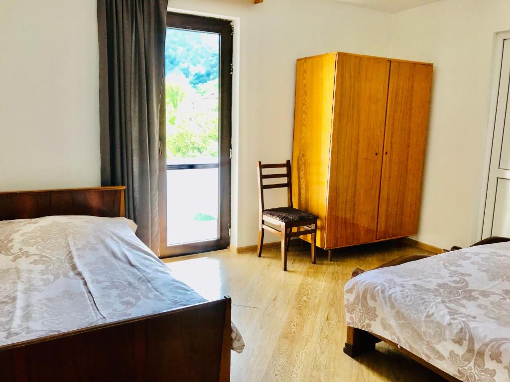 ein Schlafzimmer mit einem Bett, einem Stuhl und einem Fenster in der Unterkunft Zviad Guest House in Bordschomi