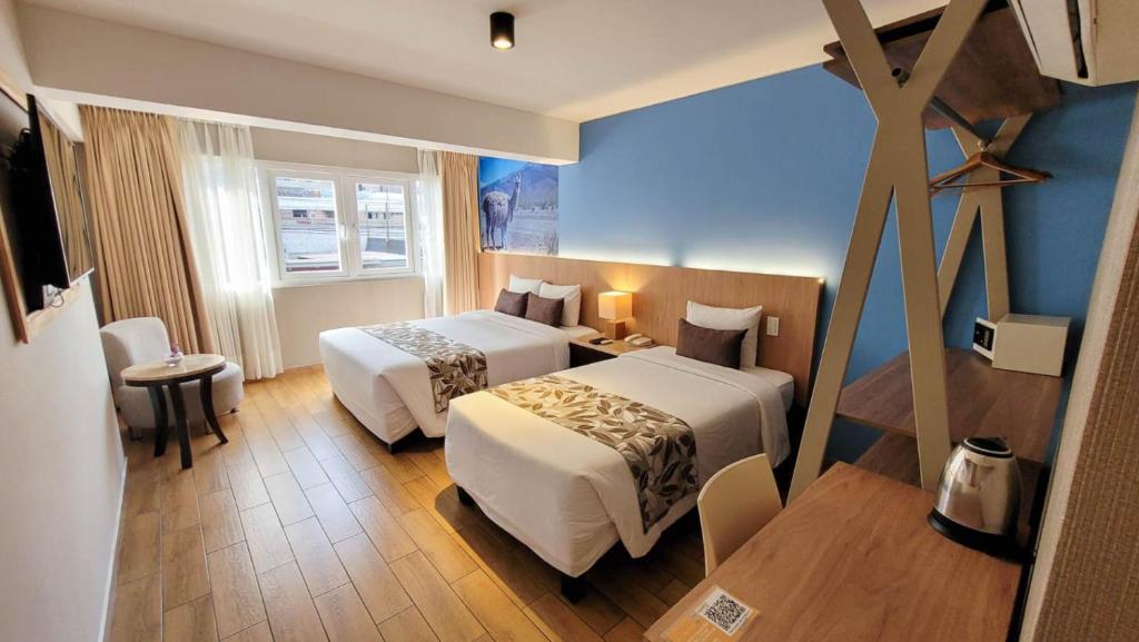 una habitación de hotel con 2 camas y una cruz en la pared en Hotel El Tambo 2 en Lima
