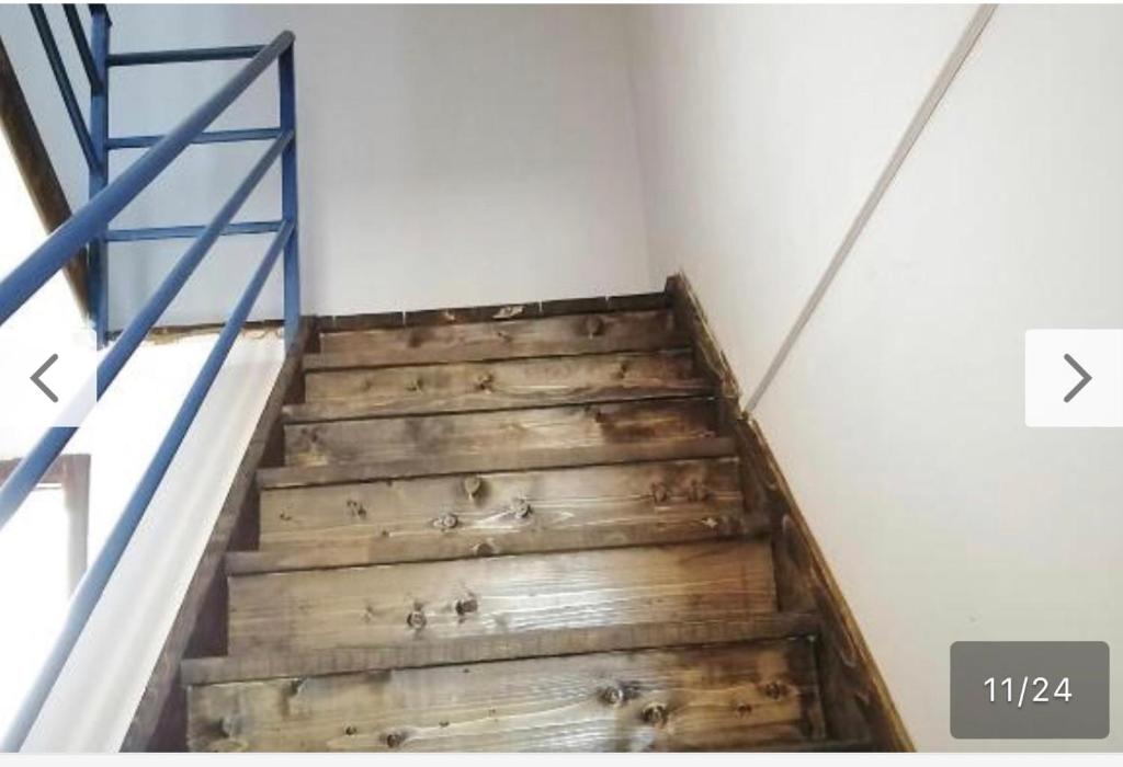 a wooden staircase in a room with a blue railing at Home guest in Tirana