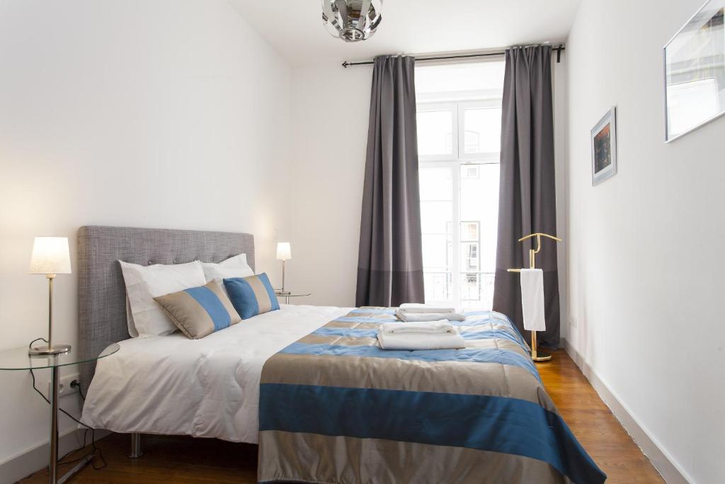 um quarto com uma cama king-size e almofadas azuis e cinzentas em Downtown Cozy Apartment em Lisboa