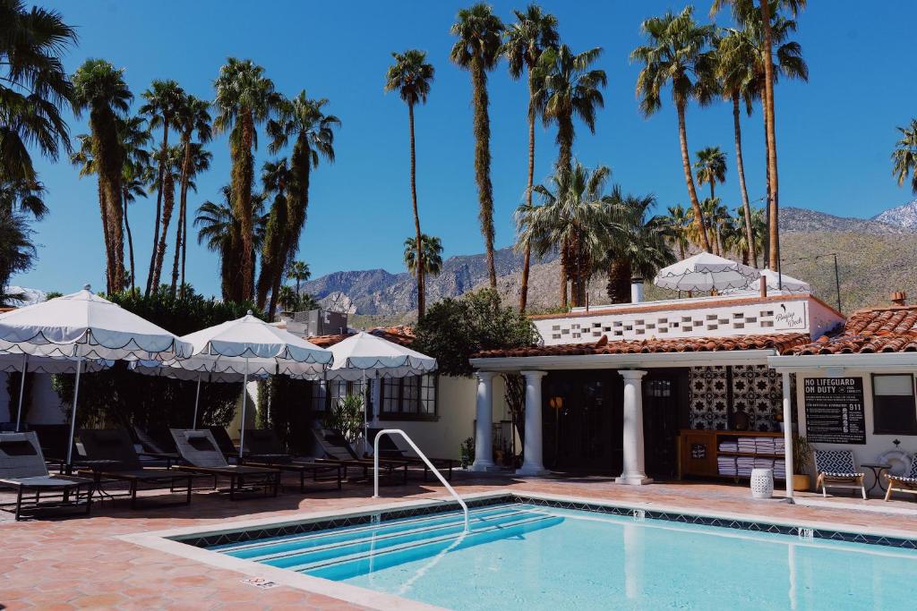 a swimming pool with palm trees and a house at Villa Royale in Palm Springs