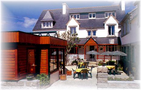 a large house with tables and chairs in front of it at Les Ondines in Saint-Guénolé