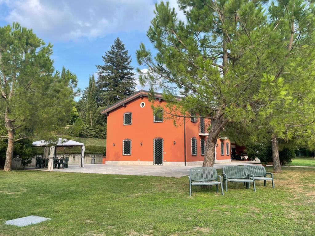 an orange building with two benches in front of it at Ca' degli Ulivi in Creazzo