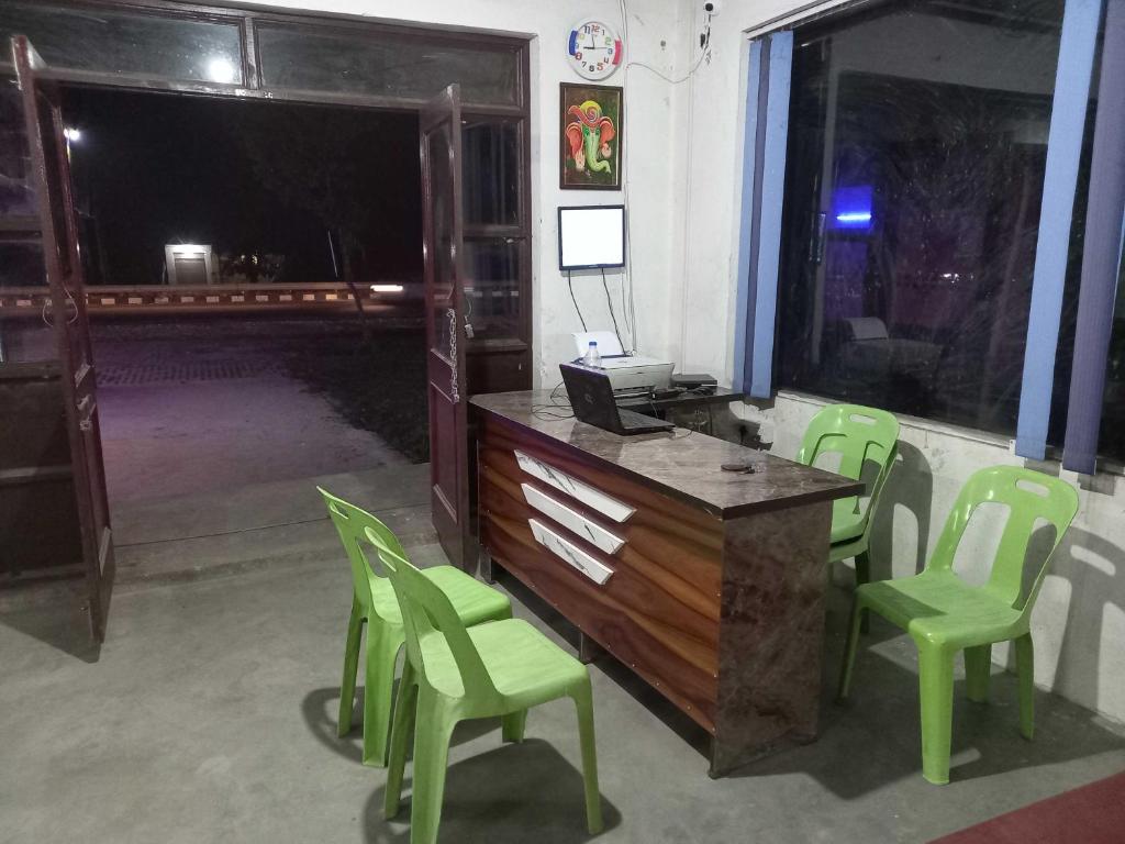Habitación con escritorio con sillas verdes y ventana. en OYO 81031 Golden Hotel And Restaurant, en Muzaffarnagar
