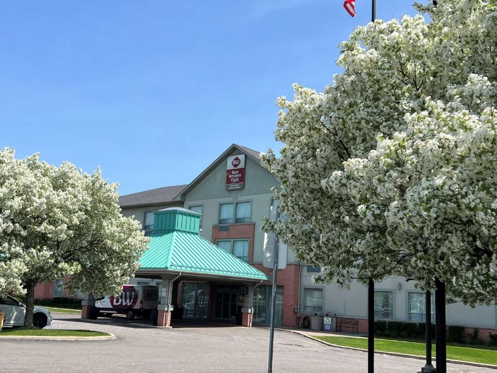 a hotel with flowering trees in front of a building at Best Western Plus Travel Hotel Toronto Airport in Toronto