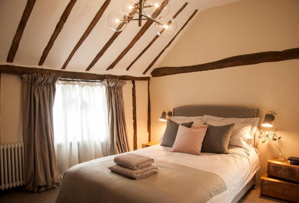 a bedroom with a large bed with a ceiling at Blacksmith's Cottage Suffolk in Lavenham